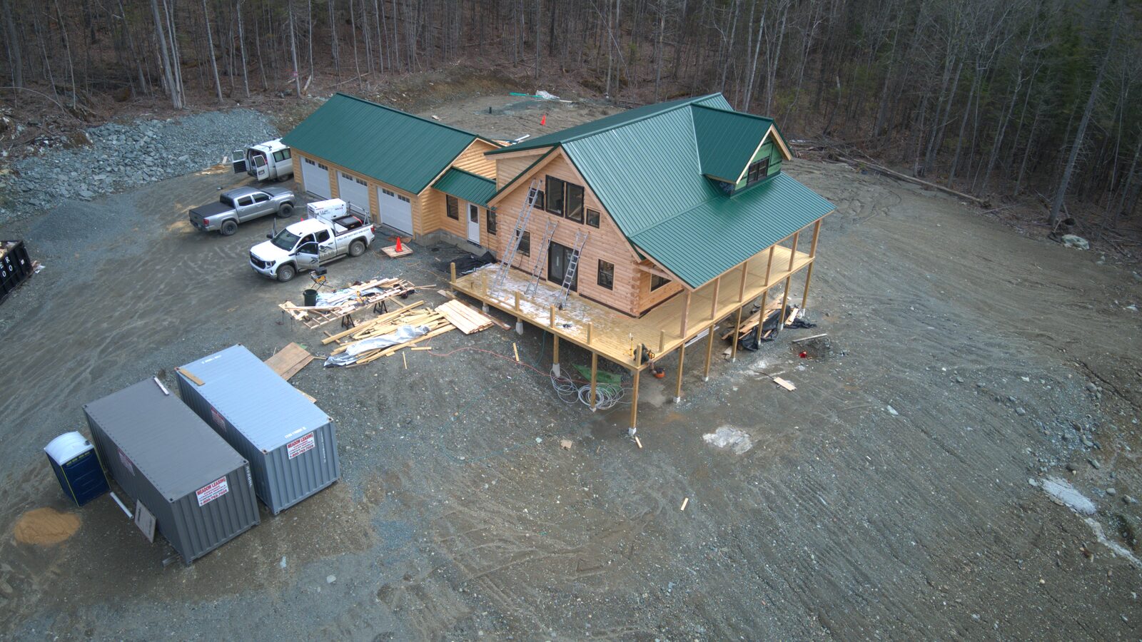 Aerial of a custom log home with a green metal roof under construction