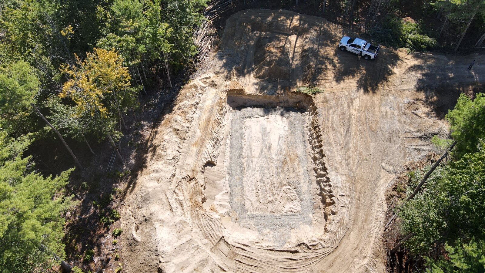Aerial of a cleared site with footings and an excavator