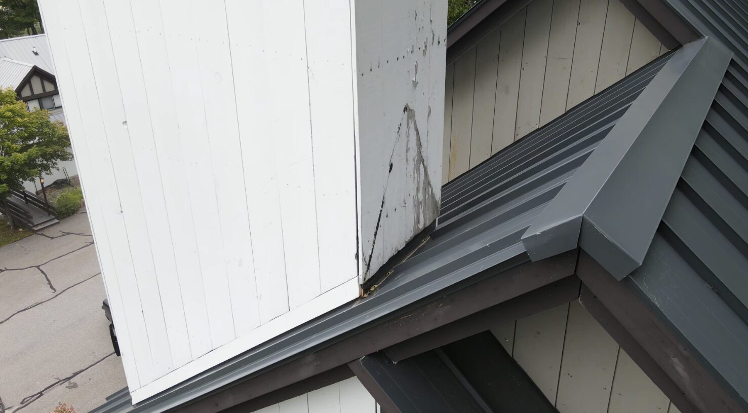 Aerial of a metal roof ridge and siding showing water staining
